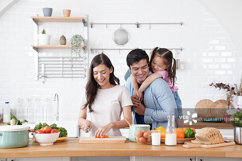 幸福家庭，父亲给女儿骑小猪，妻子在一旁做饭图片素材