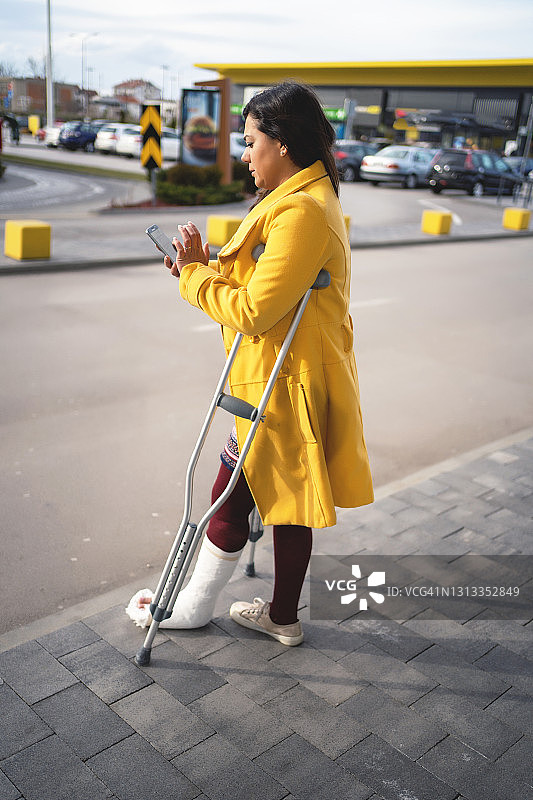 脚上打着石膏用手机的女人图片素材