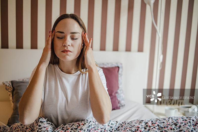 年轻女子卧床头痛图片素材