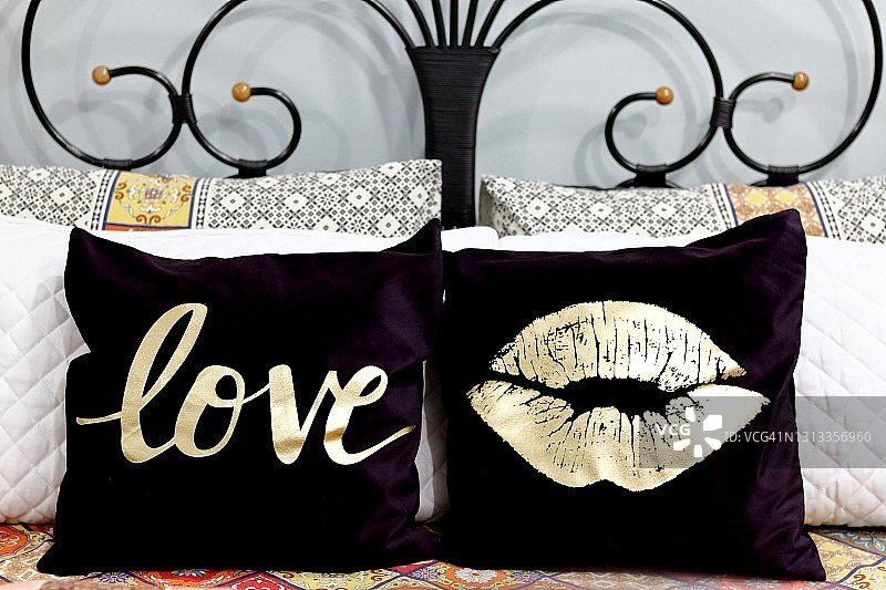 印有爱心和嘴唇图案的靠垫，置于铁艺床上图片素材