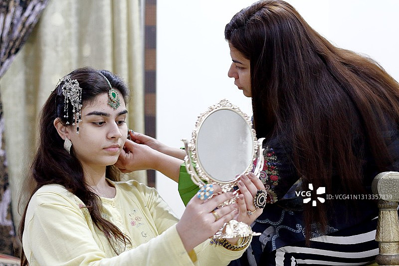 女人帮助年轻女子佩戴传统首饰图片素材