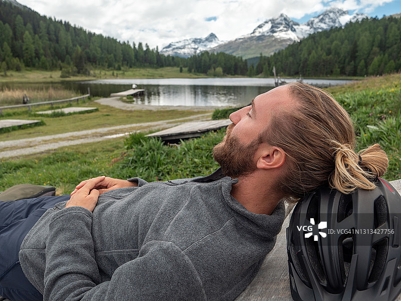 在湖岸边闭目放松的年轻男人图片素材