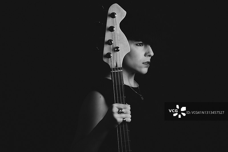 手持贝斯吉他的严肃女人侧面照图片素材