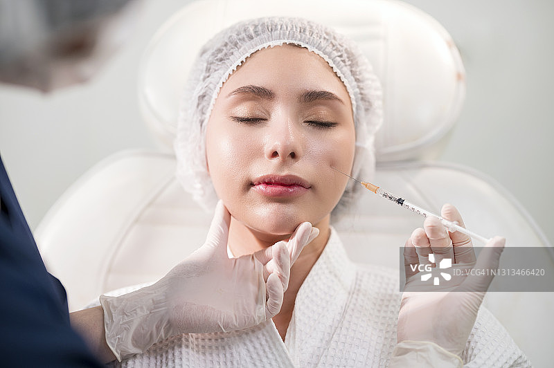 在美容诊所，护士为美丽女人注射肉毒杆菌，进行面部护理图片素材