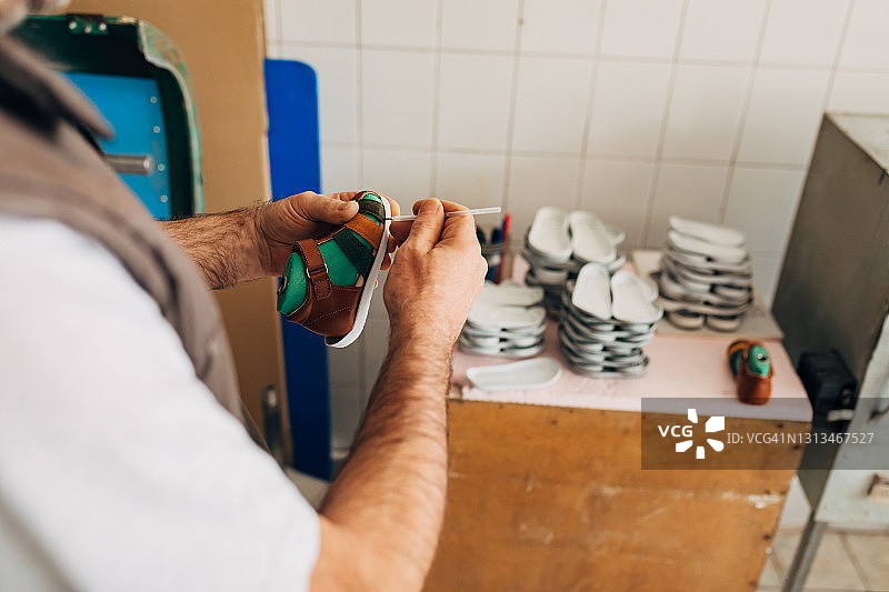 专业鞋匠在童鞋工坊清理鞋底胶水图片素材