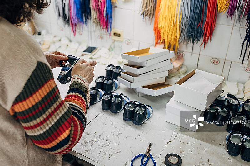 儿童鞋厂的中年女工正在检查新款童鞋的质量图片素材