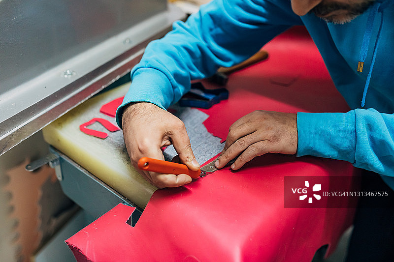 鞋匠从粉色皮革上裁剪鞋样，制作新款夏季童鞋图片素材