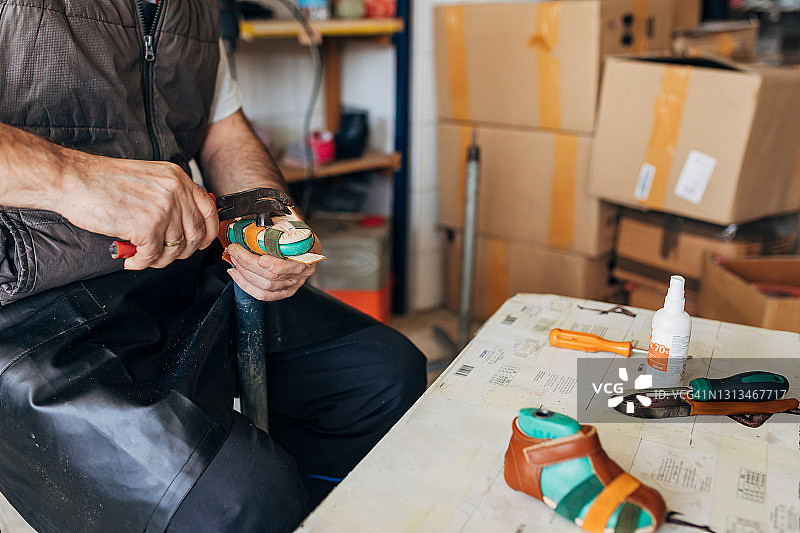 在童鞋厂，专业鞋匠用钳子收紧塑料模特的凉鞋图片素材