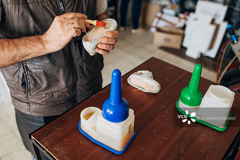 鞋匠用刷子和工业胶涂抹皮革鞋底，为下一步生产做准备图片素材