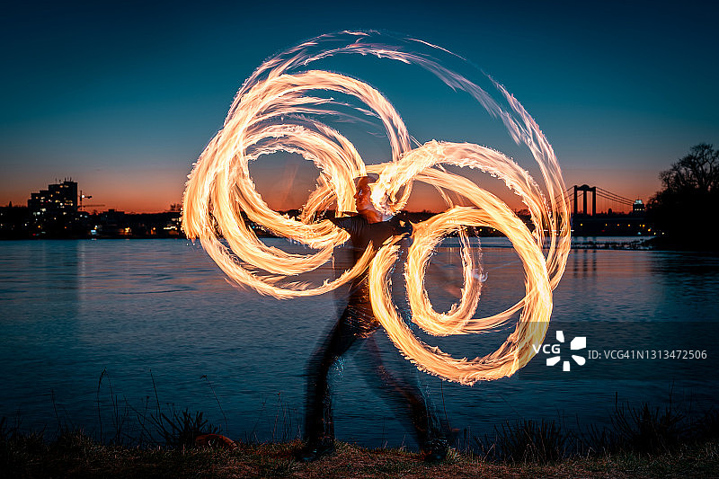 女性火焰艺术家在黄昏时创造火焰圈图片素材