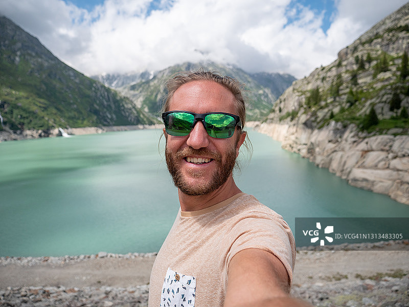 男人徒步旅行时在高山湖泊自拍图片素材
