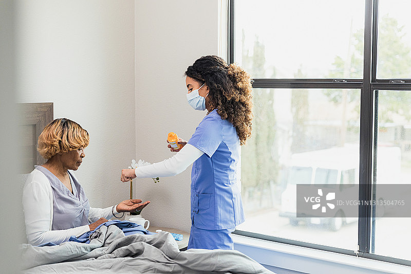 护士上门拜访时给卧床不起的病人递送药物图片素材