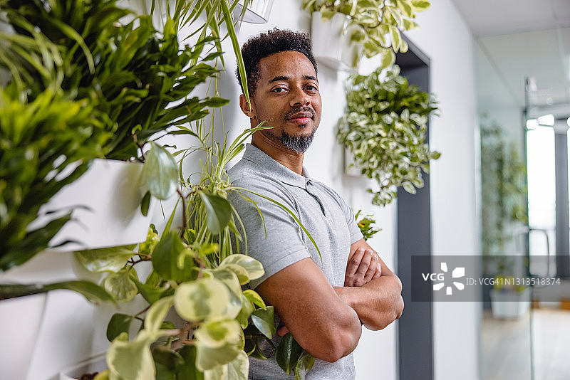 植物墙前中年混血男商人侧面照图片素材