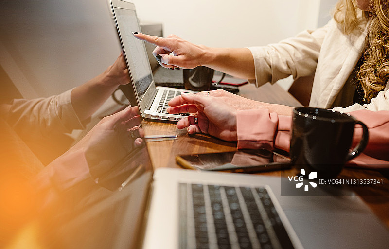 两位年轻女商人工作和喝咖啡的特写，营销策略头脑风暴，团队合作赋予女性力量。图片素材