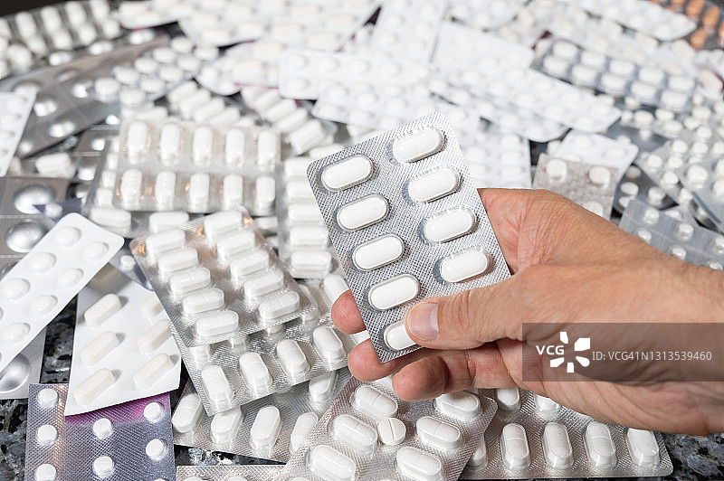 男人手拿封装药丸，大量药丸图片素材