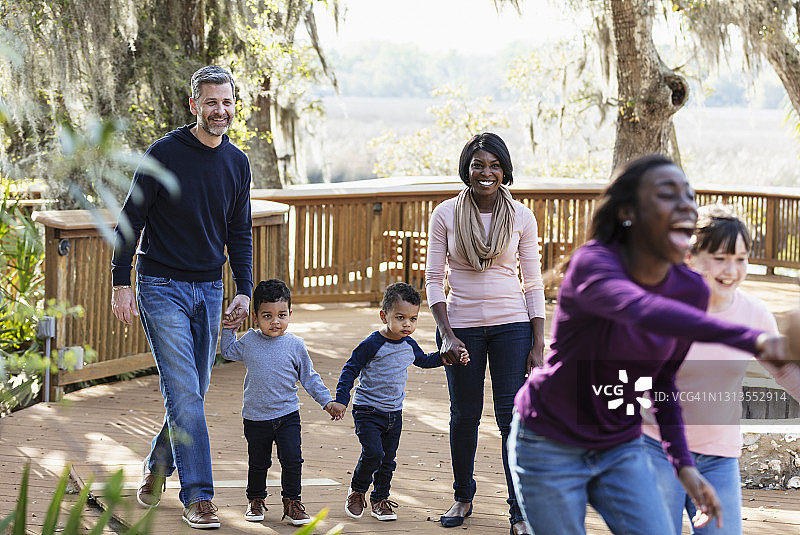 在公园里步行的有五个孩子的混合家庭图片素材