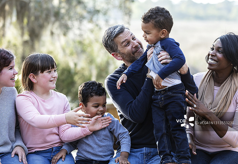 有四个孩子的重组家庭坐在公园长椅上图片素材