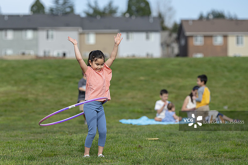 公园里玩呼啦圈的可爱混血小女孩图片素材