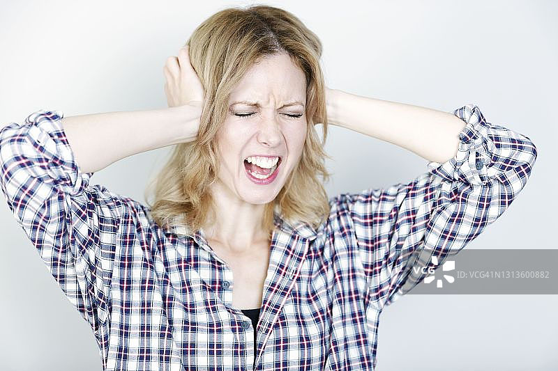 年轻女人捂着头，看起来痛苦而沮丧图片素材