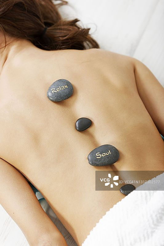 年轻女人享受热石背部按摩图片素材