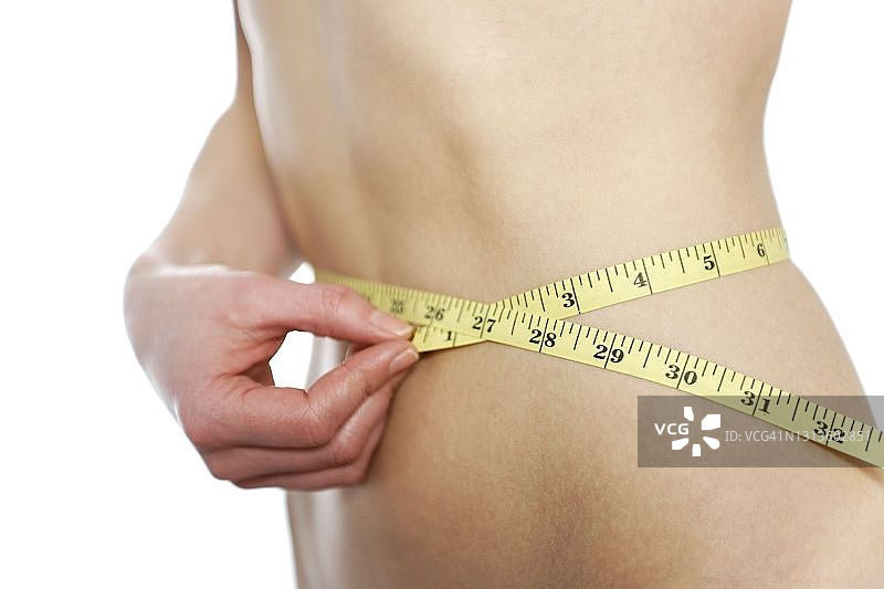 年轻女人测量身体，作为节食的一部分图片素材