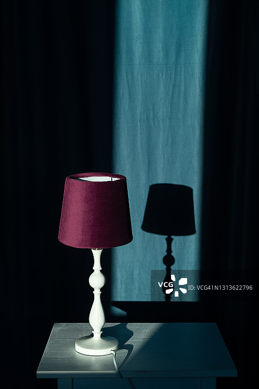 紫色灯罩的台灯立于床头柜，光影室内设计图片素材