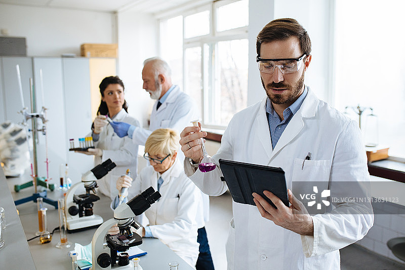 在实验室用试管做实验的年轻男科学家图片素材