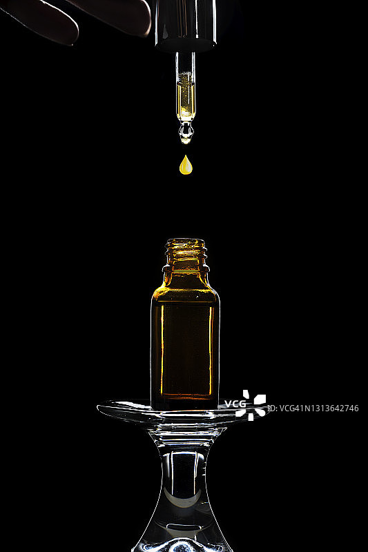 用于水疗护理的按摩油或面部精华油瓶，深黑色背景。图片素材