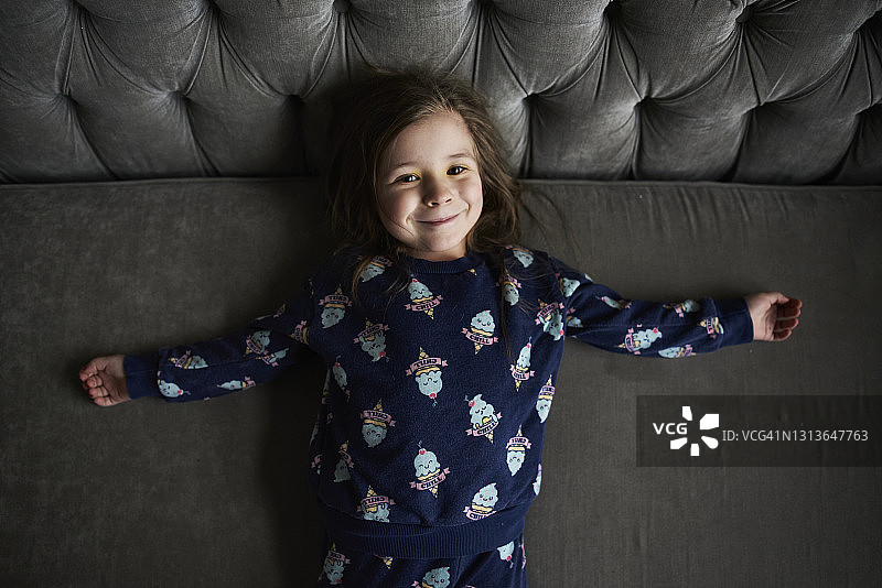 穿着睡衣躺在沙发上的微笑女孩图片素材