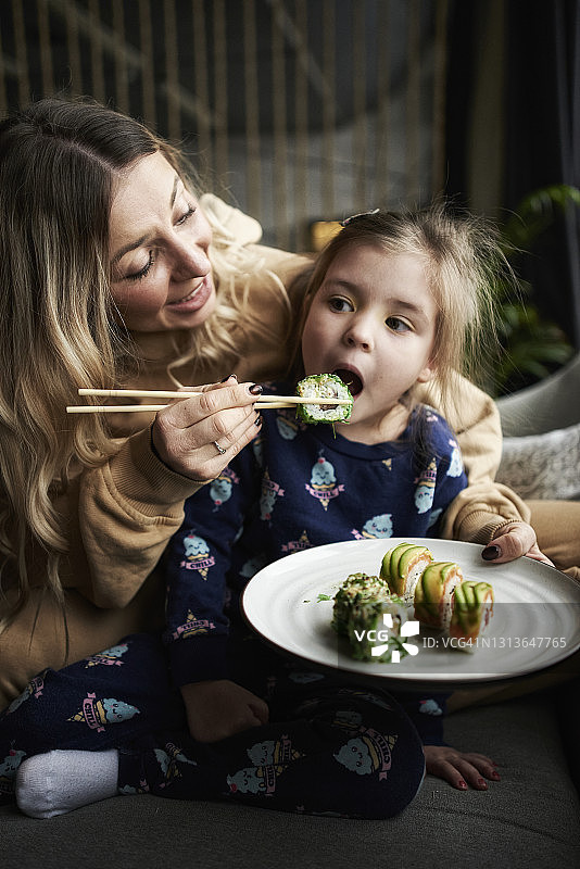 母亲喂女儿吃寿司卷图片素材