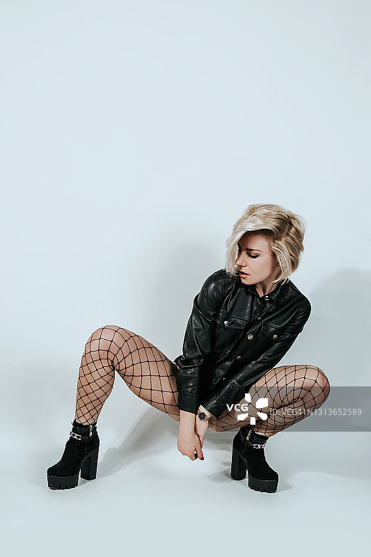 留时尚发型的年轻女子蹲着看向侧面图片素材