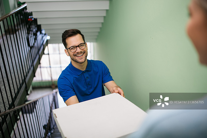 年轻白人披萨外卖员工作中的高角度视图图片素材