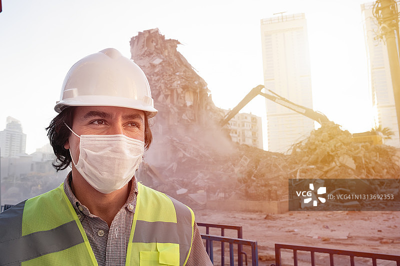 戴口罩的工程师在建筑工地，背景是机械设备图片素材
