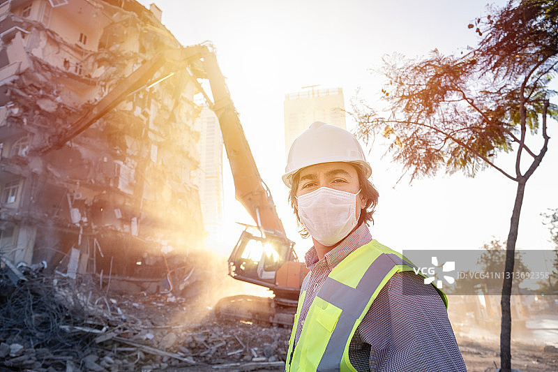 戴口罩的工程师在建筑工地，背景是机械设备图片素材