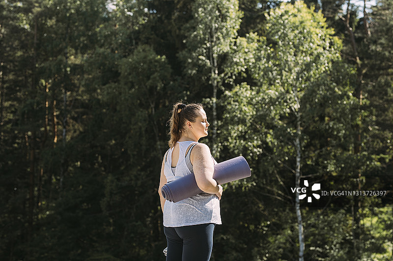 自然瑜伽：手持卷起的瑜伽垫的女人图片素材