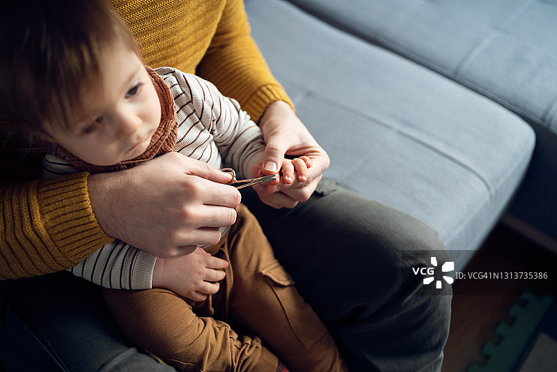 父亲从高角度为婴儿剪指甲图片素材