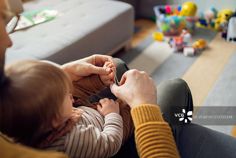 父亲给男婴剪脚趾甲的俯视照片图片素材