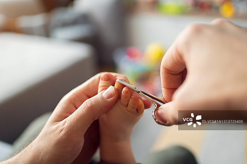 父亲用剪刀剪儿子脚趾甲的特写图片素材