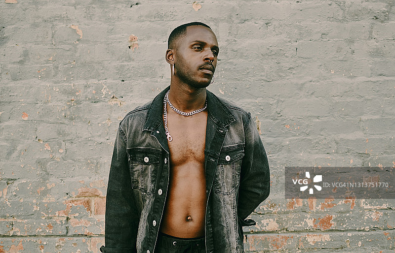 阳光下靠墙而立的英俊年轻男人图片素材