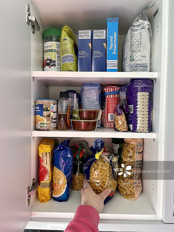 手伸向厨房橱柜里的意大利面图片素材