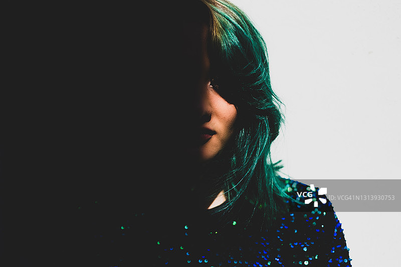 在墨西哥城看着镜头的绿色头发年轻女人，脸被阴影遮蔽图片素材