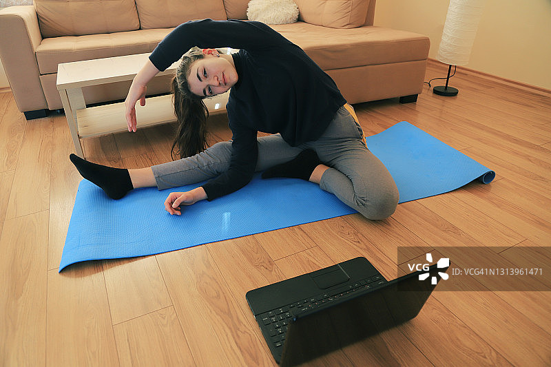 年轻女孩在家通过网络做运动图片素材