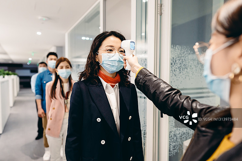 亚洲商务人士在办公室测量体温图片素材
