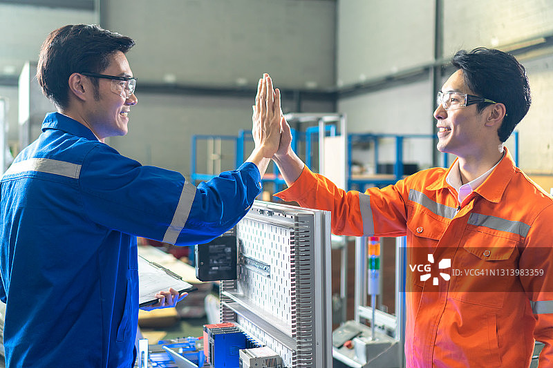 两名工业工程师在工厂里用碰拳的方式互相问候。图片素材