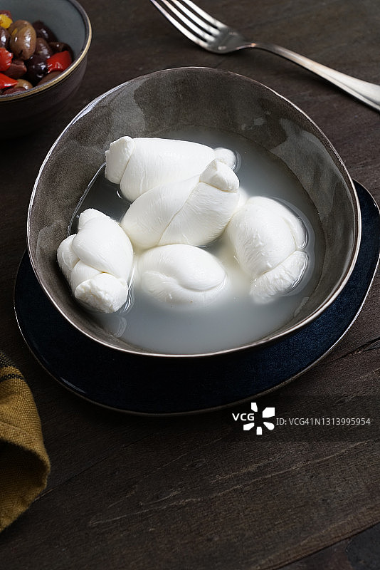 水牛奶酪结，来自坎帕尼亚的特色产品，搭配深色木质背景上的香辣调味橄榄，意大利，欧洲图片素材