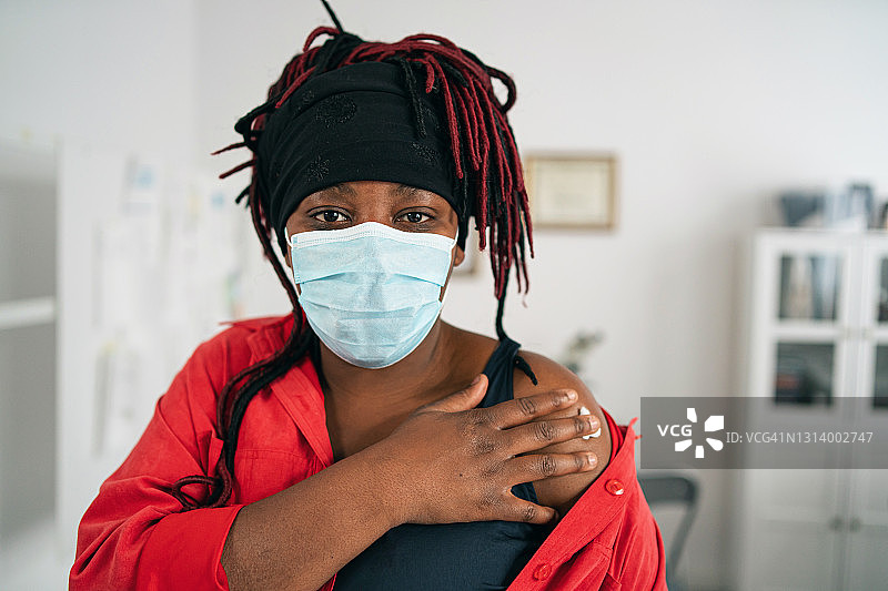 中年非洲裔女性戴防护口罩在医生办公室接种新冠疫苗图片素材