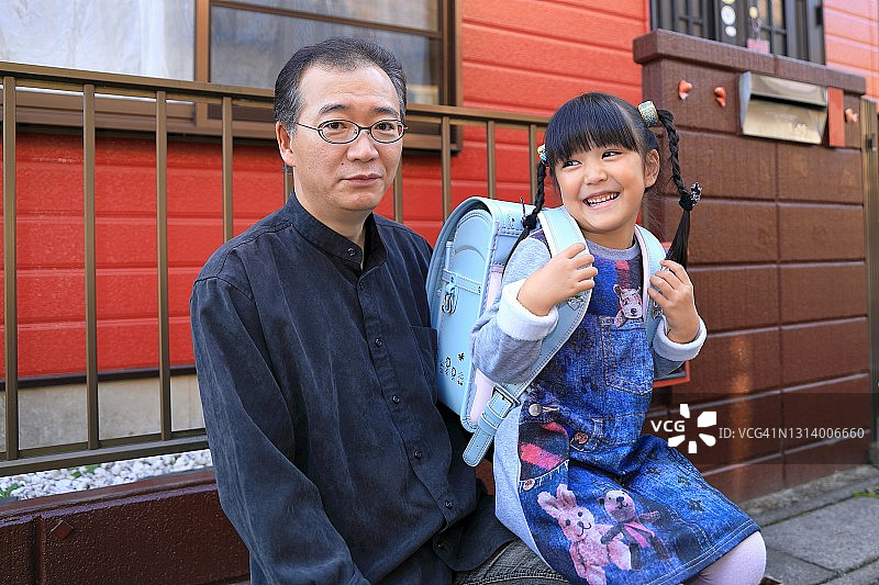 笑着的一年级学生和她的父亲背着书包图片素材