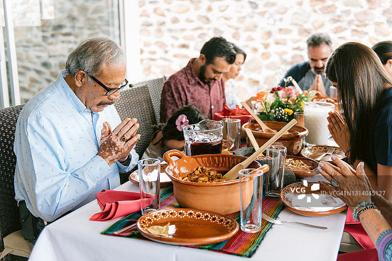 多代同堂家庭在晚餐前祈祷图片素材