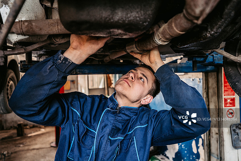 汽车修理工在车间用灯检查汽车图片素材