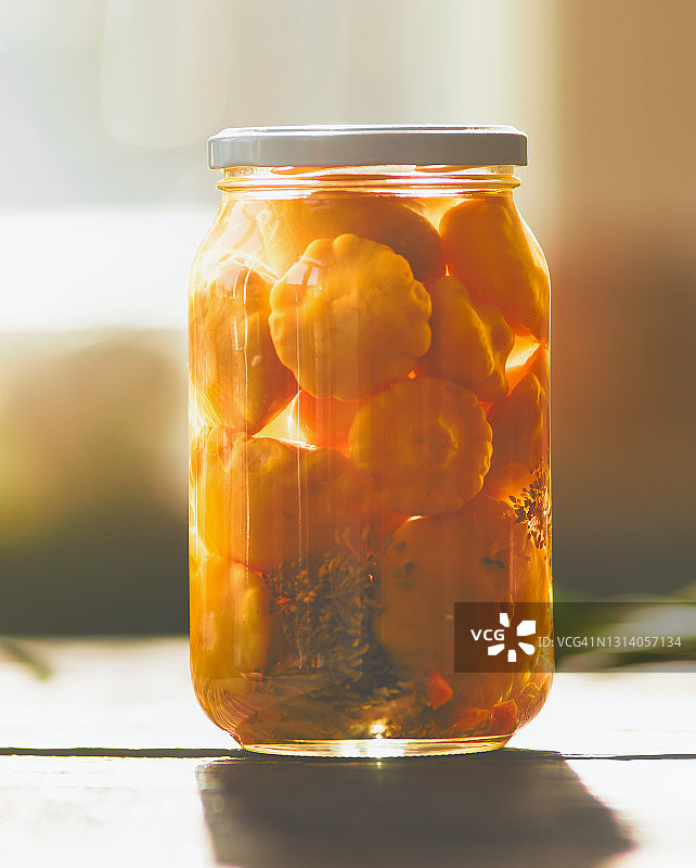 厨房窗边玻璃罐中的腌制黄色南瓜图片素材